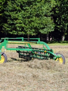 Next, windrows are made out of the dry, cut hay. Windrows are rows of hay raked up and shaped before being baled. Attached to a tractor, Phurba pulls the bar rake at an angle and makes windrows from the tedded hay.