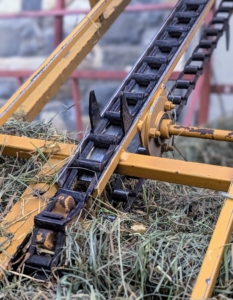 A hay elevator is an open skeletal frame, with a chain that has dull three-inch spikes every few feet to grab bales and drag them along.