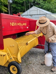 Chhiring oils the hay equipment to repel water, slow oxidation, and prevent corrosion during the off season.