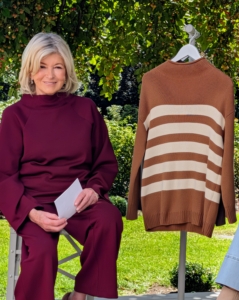 Here I am next to my 100% Cotton Roll Neck Striped Sweater. It features dropped shoulders with full length sleeves and a modern bold striped detail in the front. Get it in all the colors. This is fox trot, but it also comes in midnight navy and sea turtle with coordinating colored stripes.