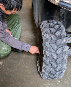 Nearby, Pasang checks the tires on this Polaris off-road vehicle. He adds air where needed.