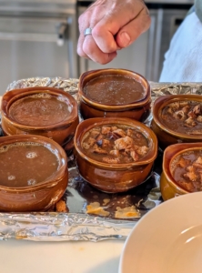 Once the soup is poured into the crocks, Jeff drops a handful of croutons in each bowl.