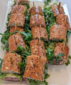 Current provided lunch and small bites including an artisanal sandwich buffet. This is a platter of Tuscan Caprese sandwiches made with fresh mozzarella, arugula, basil, roasted tomatoes, and pesto.