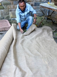 Pete cuts a piece of burlap to drape over the pot. Burlap is available in giant rolls of 40-inches or 60-inches wide. Also called hessian, burlap is made in Pakistan, Bangladesh and India from jute, a tall, grass-like plant grown for its strong fibrous stalks.