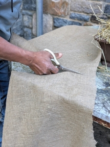 Pete makes a slit down the center of the burlap piece to accommodate the base of the tree.